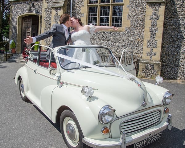 Bride and groom celebrating in vintage car at Oxted