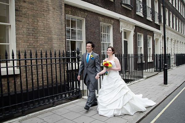 Bride and groom walking along the pavement outside wedding venue in London