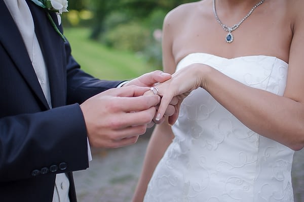 Groom placing wedding ring on brides finger at East Court