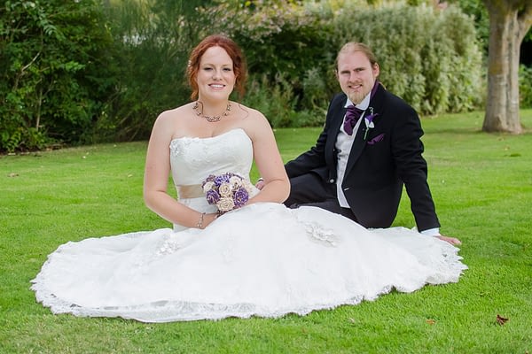 Bride sat on floor with dress fanned out and Groom behind