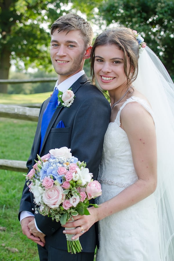bride behind groom holding bouquet at caterham wedding