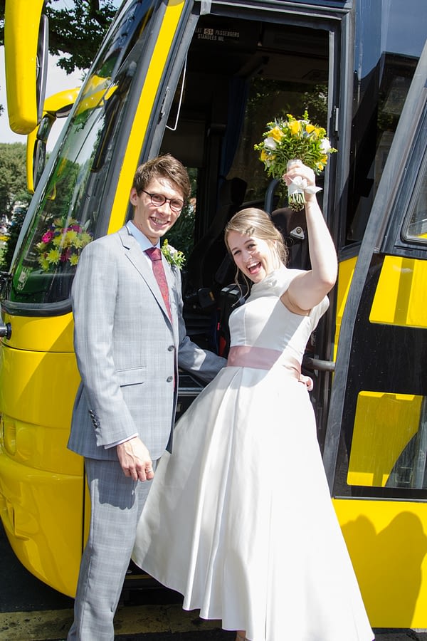 Bride and groom boarding wedding bus